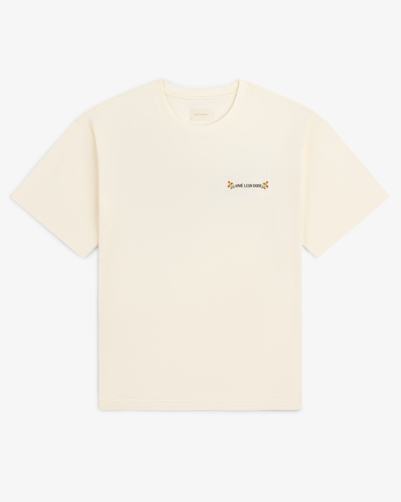 Aimé Postcard Tee: cream short-sleeve shirt with small text and a flower on the left chest.