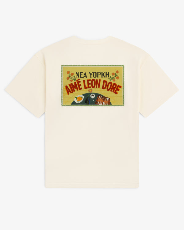 Cream Aimé Postcard Tee featuring a colorful postcard graphic and "Nea Yopkh Aime Leon Dore" on the back.