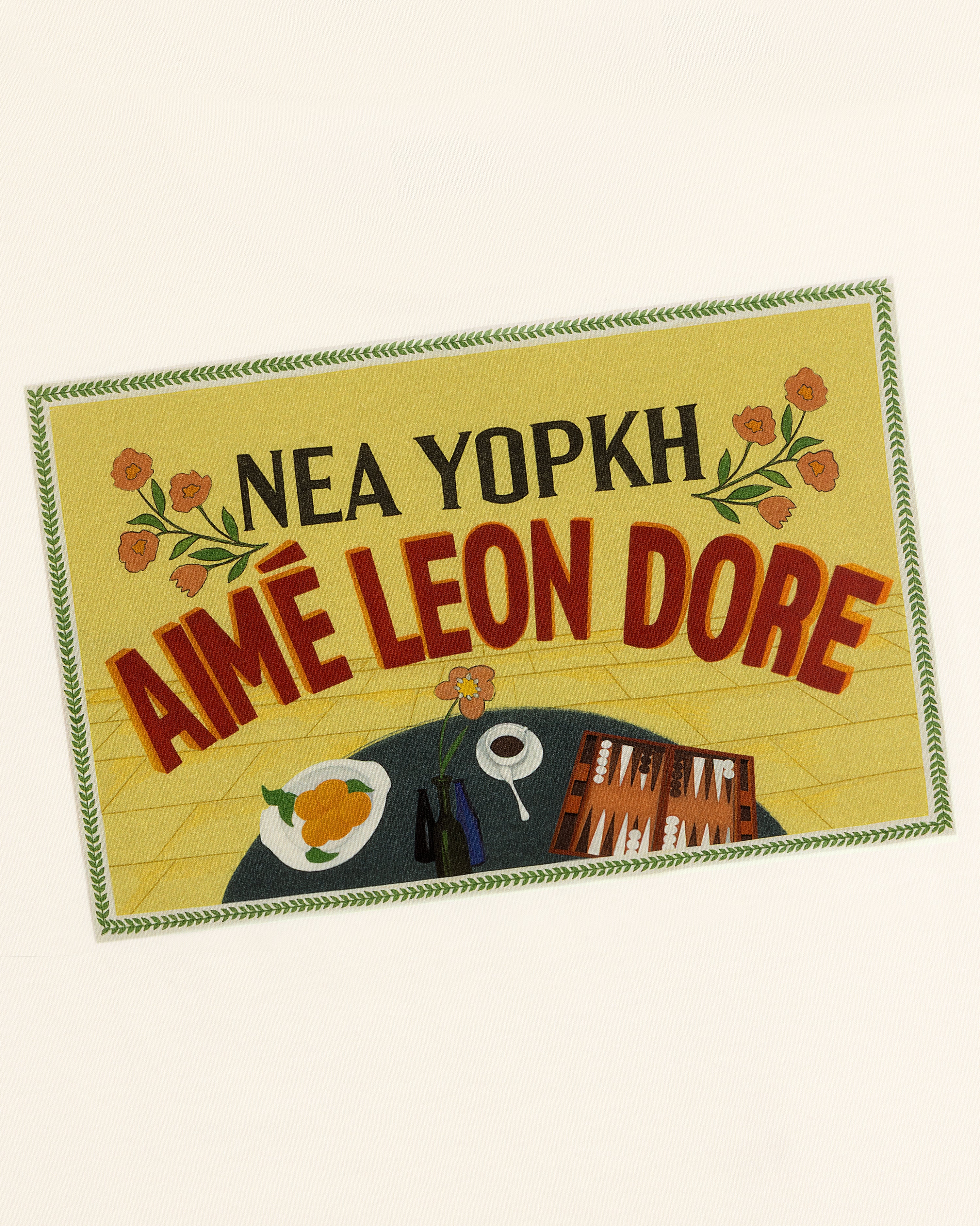 A yellow sign with flowers and a table is featured on the Aimé Postcard Tee by Aimé Leon Dore.