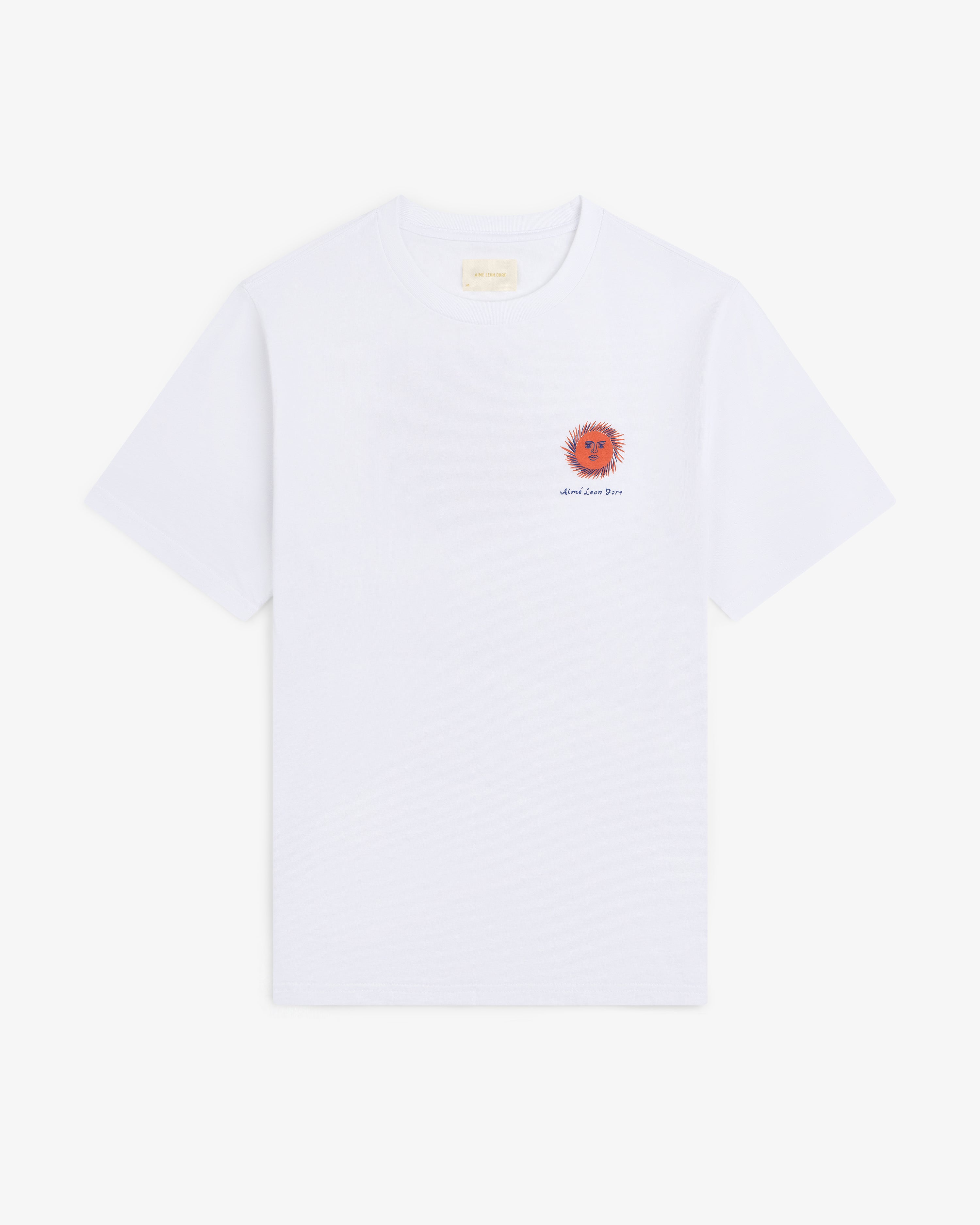 Fassianos "Sovereign Sun" Tee: white t-shirt with small red-orange sun and text on left chest, shown on plain background.