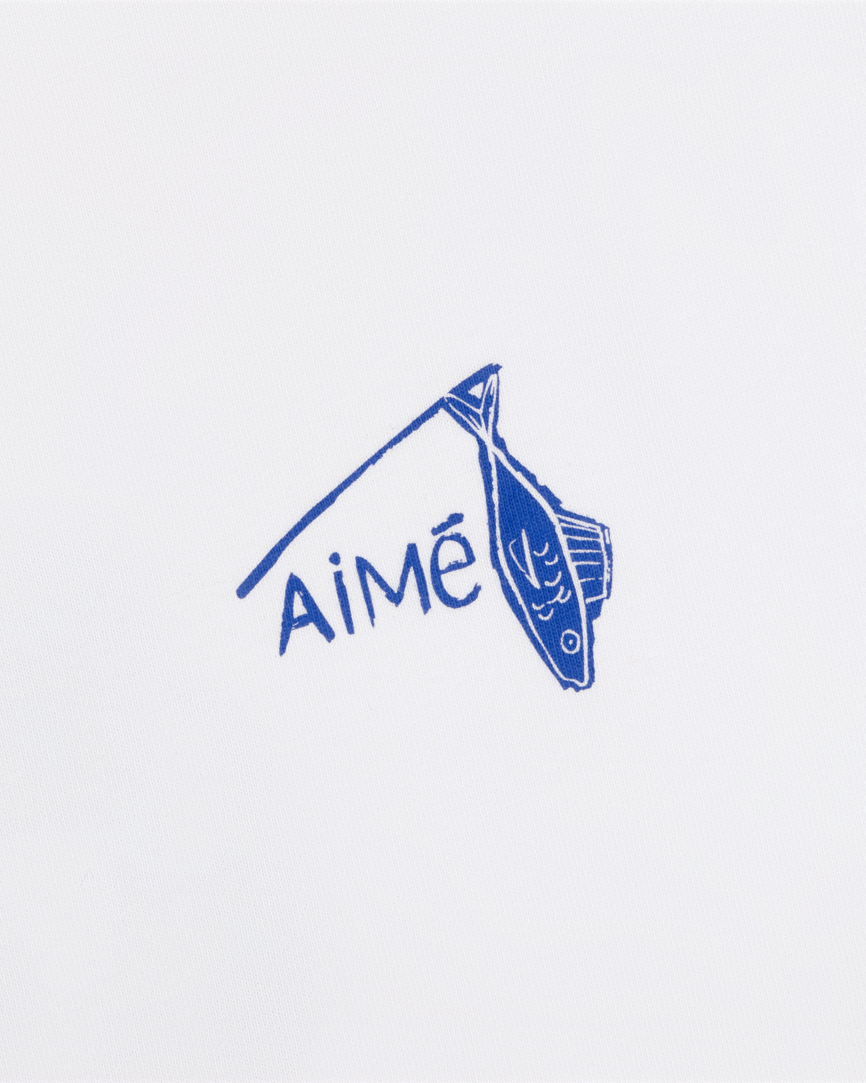 A blue fish illustration hangs on a line above the word AiMĒ on the white Fisherman Tee.