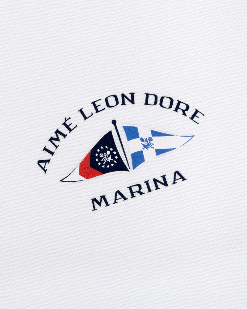 Marina Tee with embroidered Aimé Leon Dore Marina logo and two nautical flags on white fabric.