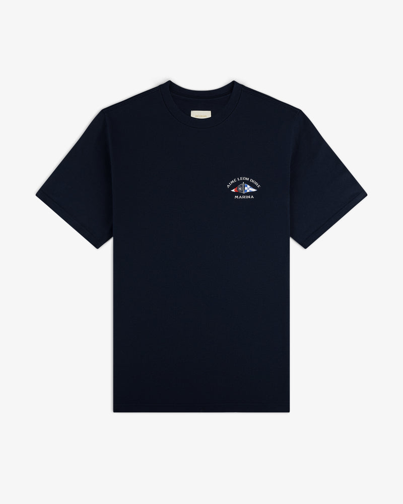 The Marina Tee is a plain black shirt with a small white graphic and text on the left chest, shown on a white background.