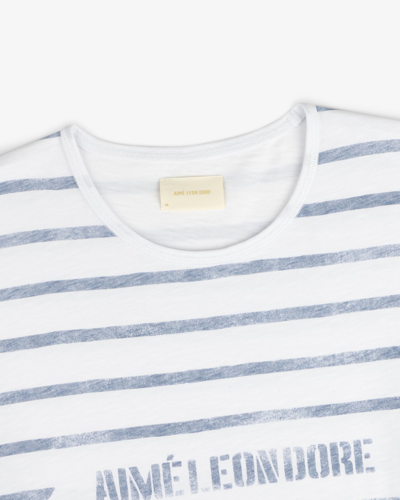 Slub Beach Tee: White T-shirt with light blue stripes and visible Aimé Leon Dore label inside the collar.