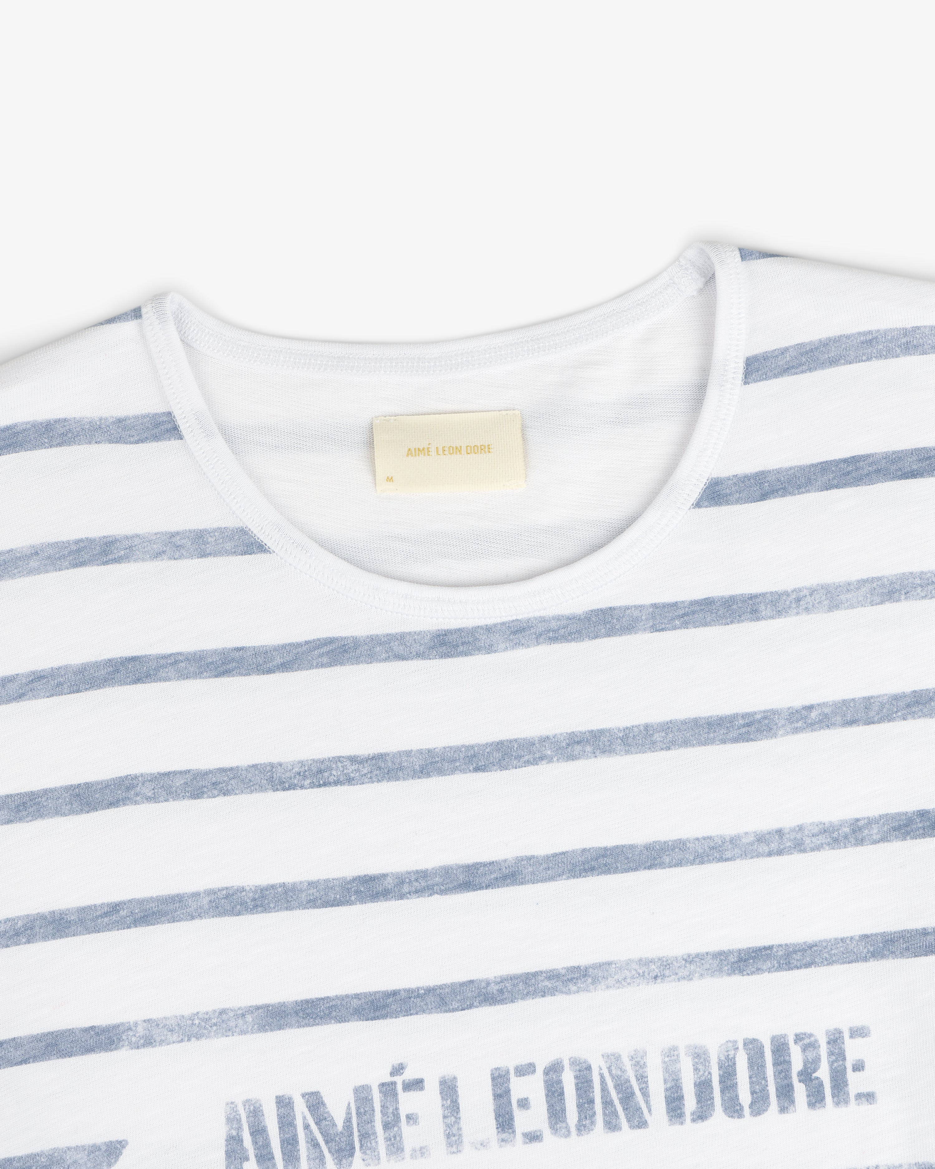 Slub Beach Tee: White T-shirt with light blue stripes and visible Aimé Leon Dore label inside the collar.