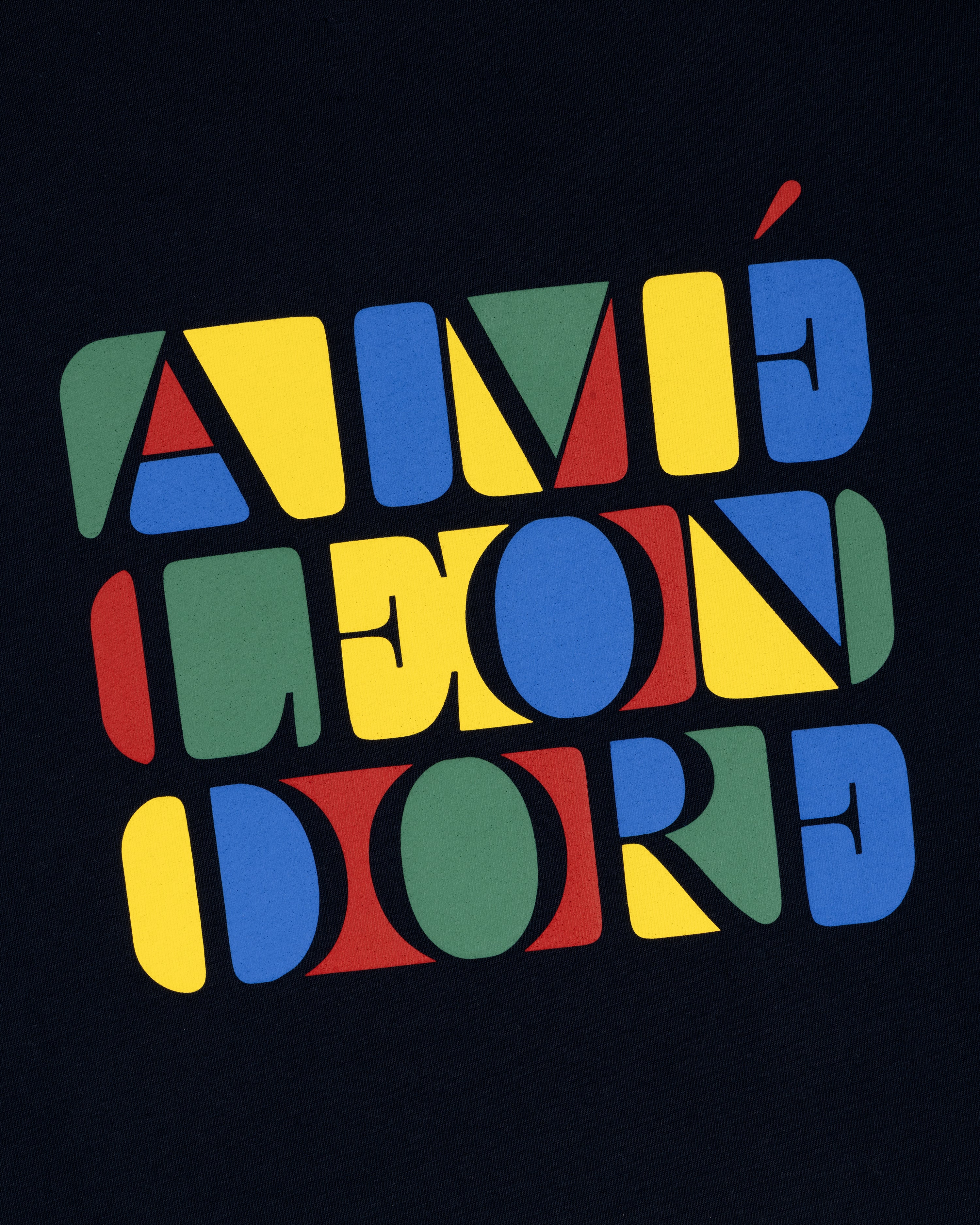 Bold, colorful “Stacked Logo Tee” text in red, yellow, blue, and green geometric letters on a black background.