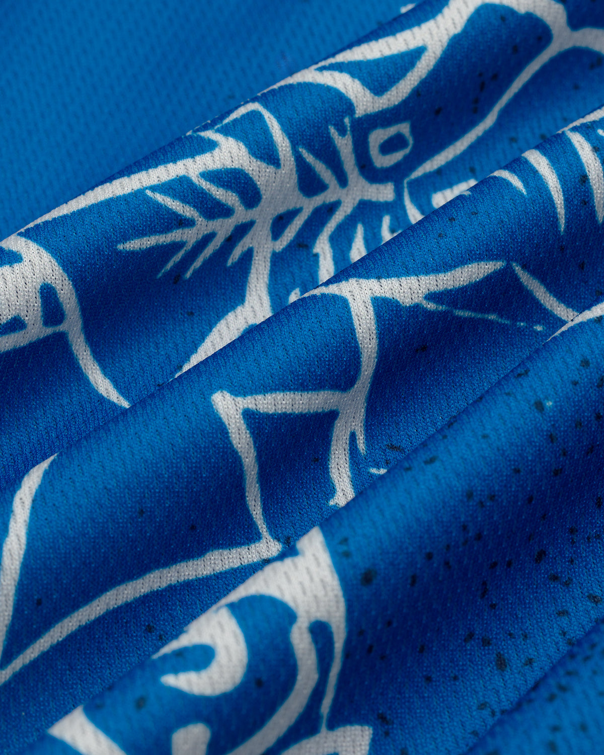 Close-up of Fassianos Half-Zip Cycling Jersey’s blue fabric with white abstract animal and nature-themed patterns.
