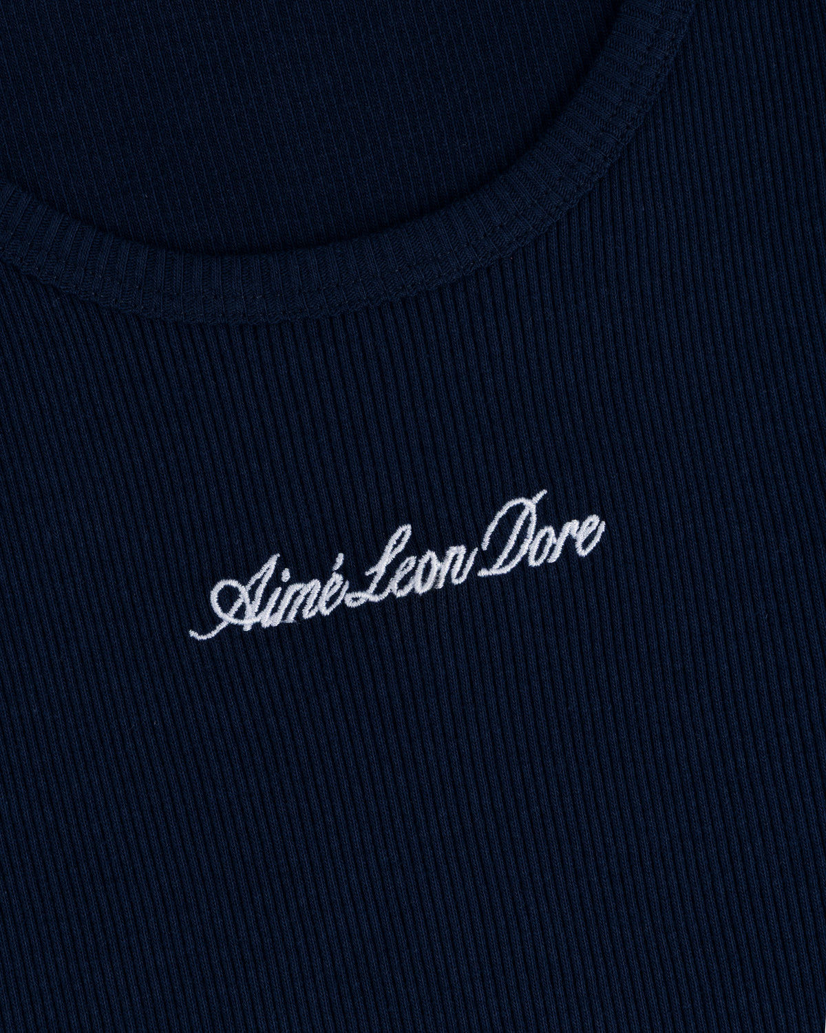 Close-up of navy ribbed fabric on the Embroidered Logo Tank Top with white Aimé Leon Dore cursive embroidery.