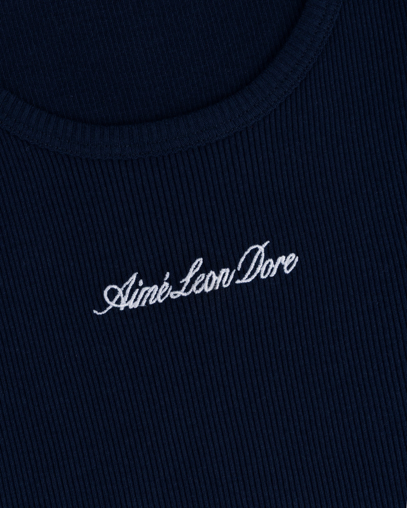 Close-up of navy ribbed fabric on the Embroidered Logo Tank Top with white Aimé Leon Dore cursive embroidery.