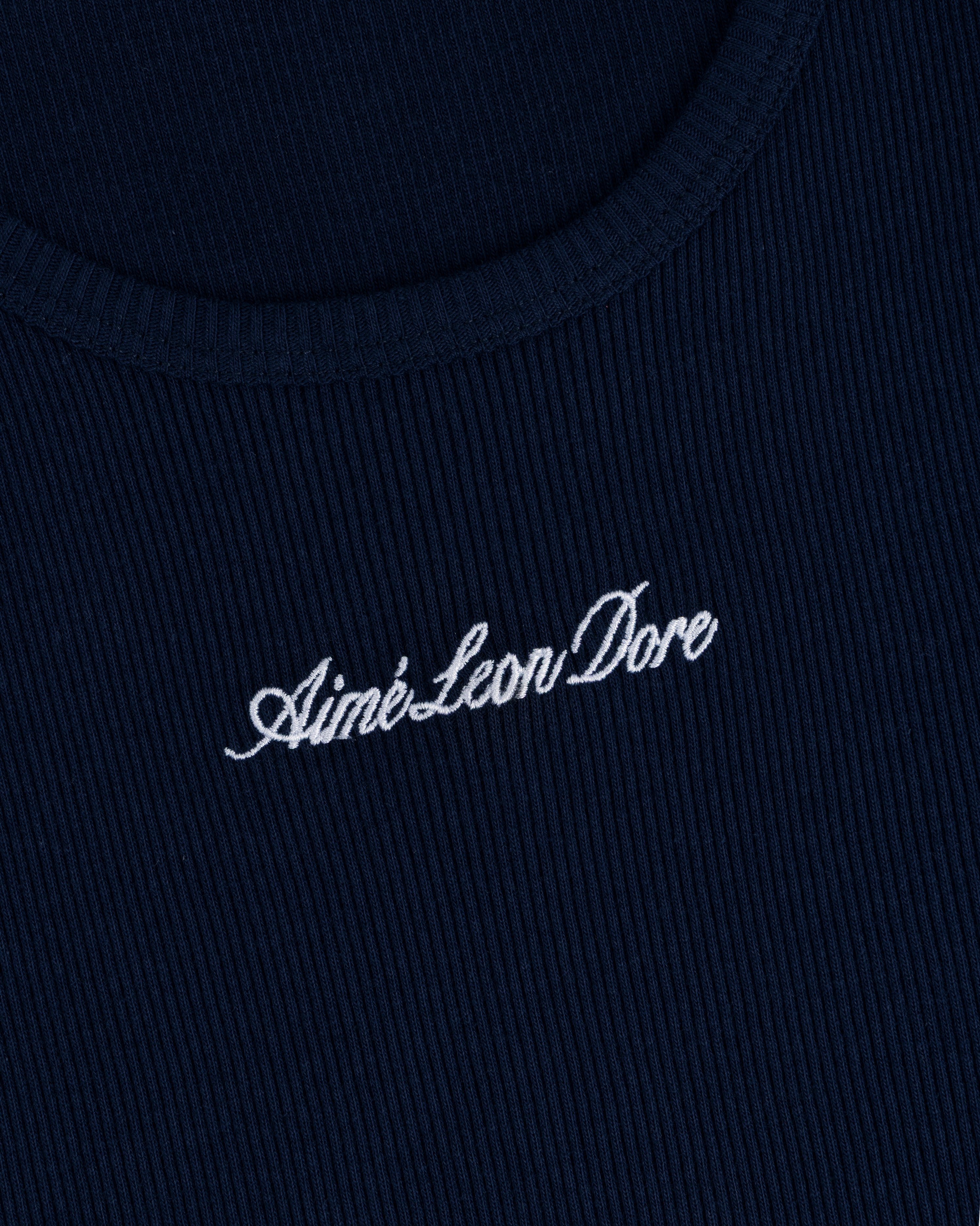 Close-up of navy ribbed fabric on the Embroidered Logo Tank Top with white Aimé Leon Dore cursive embroidery.