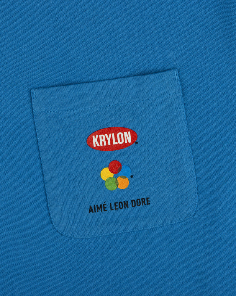 Krylon Pocket Tee: blue shirt with KRYLON logo, colorful paint blobs, and AIMÉ LEON DORE below the pocket.