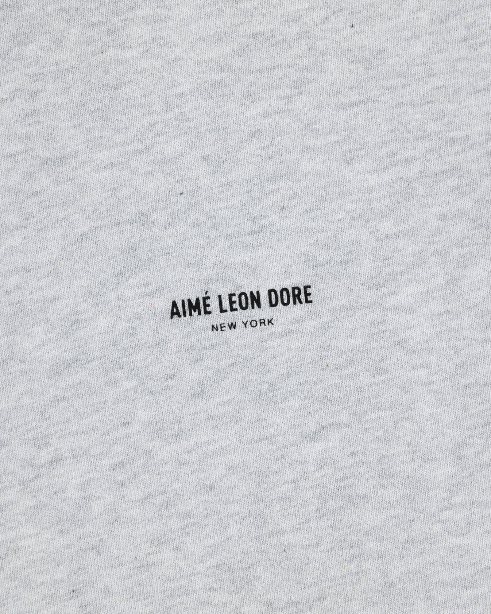 Close-up of a heather gray Long-Sleeve Micro Logo Tee with AIMÉ LEON DORE NEW YORK printed in small black text.