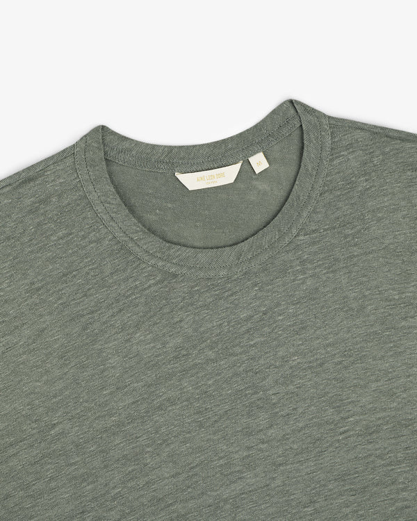 A Linen Tee in light green, crew-neck style, shown from shoulders up with a size label inside the collar.