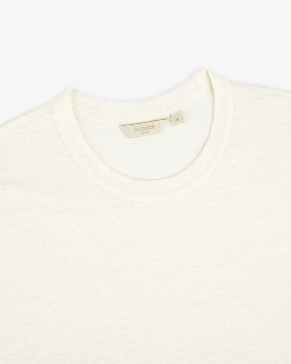 Close-up of the Linen Tee, a plain off-white crew neck T-shirt laid flat on a white background.