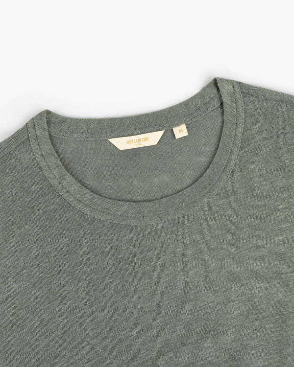 Close-up of a sage green Long-Sleeve Linen Tee with a visible beige tag inside the crew neck collar.