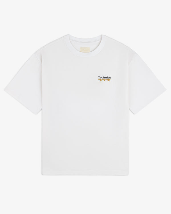 ALD / Technics Logo Tee: White tee with Technics cursive logo on left chest. Plain background.