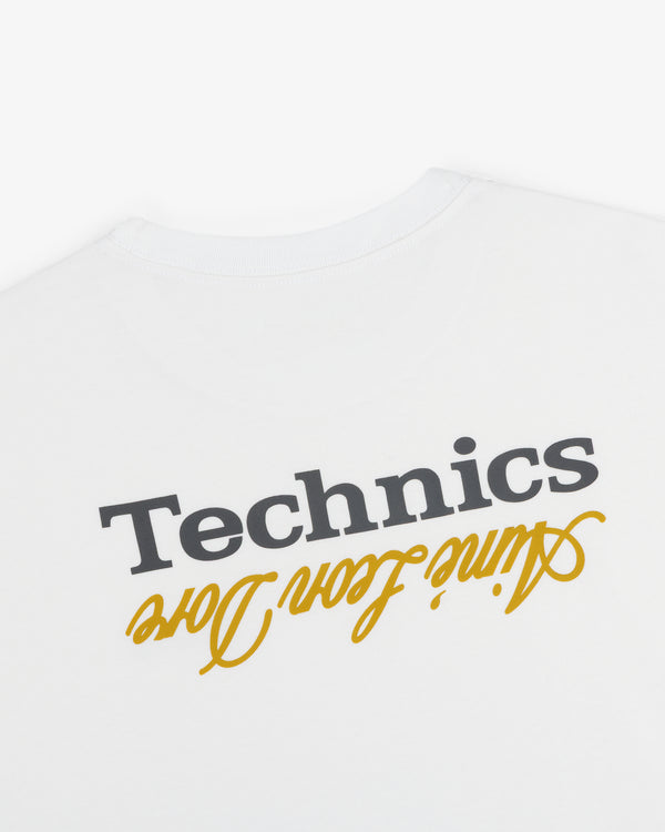 ALD / Technics Logo Tee: White shirt with black Technics and yellow ain’t from here prints, both upside down.