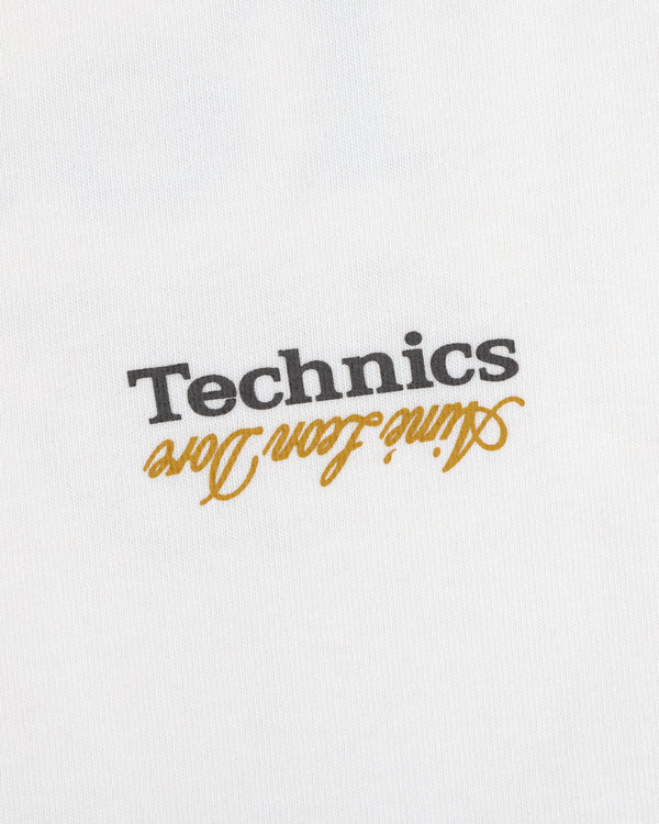 ALD / Technics Logo Tee: White fabric with black "Technics" and gold "active floor long" printed upside down.