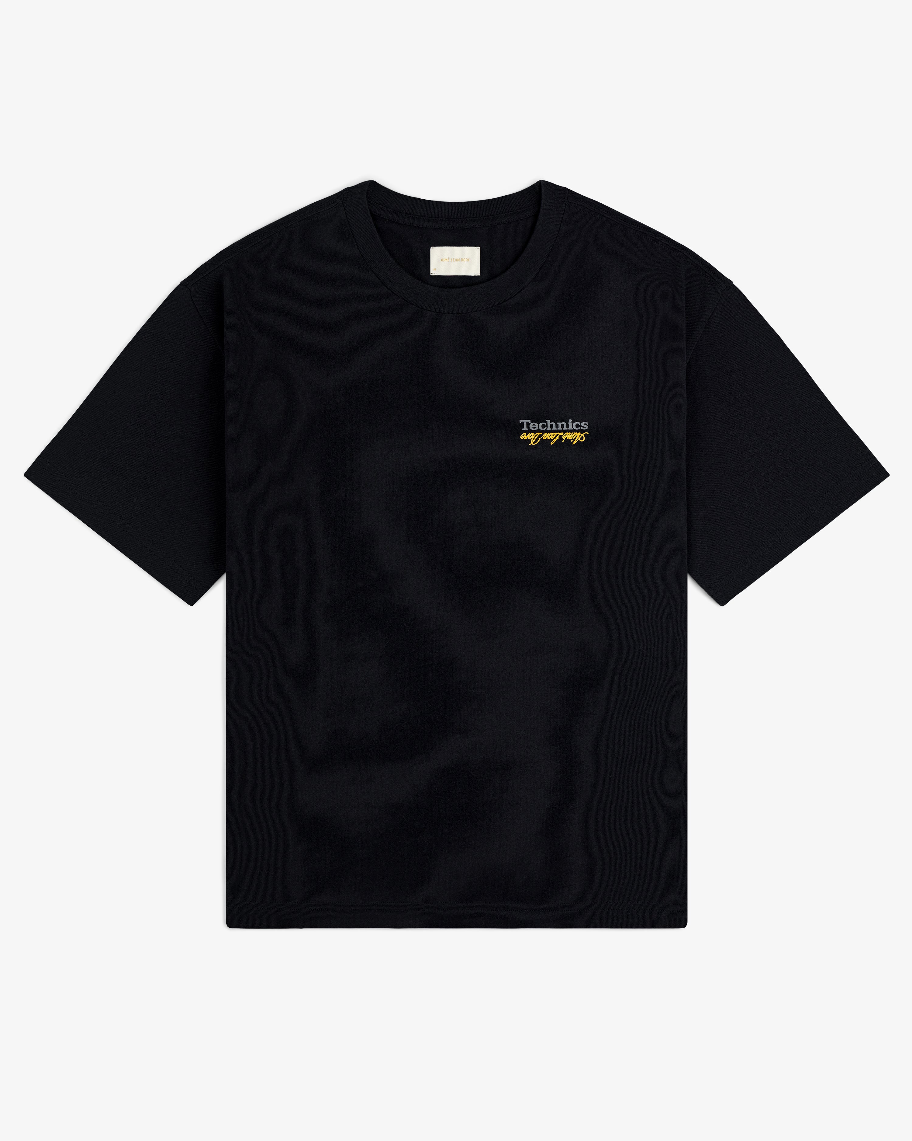 ALD / Technics Logo Tee: Black short-sleeve shirt with small white and yellow logo text on the left chest.