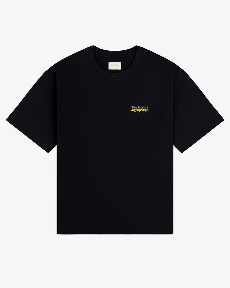 ALD / Technics Logo Tee: Black short-sleeve shirt with small white and yellow logo text on the left chest.