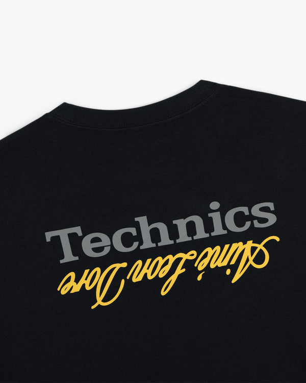 ALD / Technics Logo Tee: Black tee with gray Technics and yellow "vinyl for djs" script, both printed upside down.