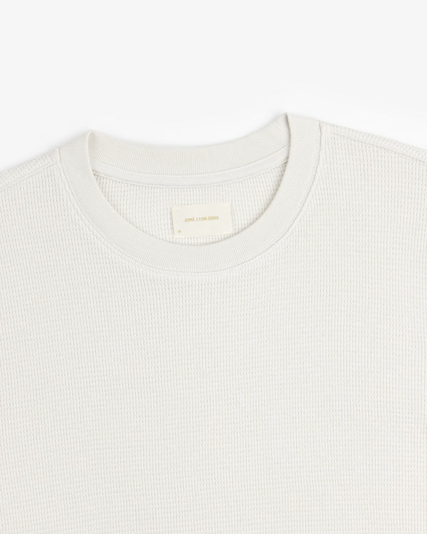 Close-up of a textured off-white Long-Sleeve Waffle Thermal with a woven label at the crewneck.