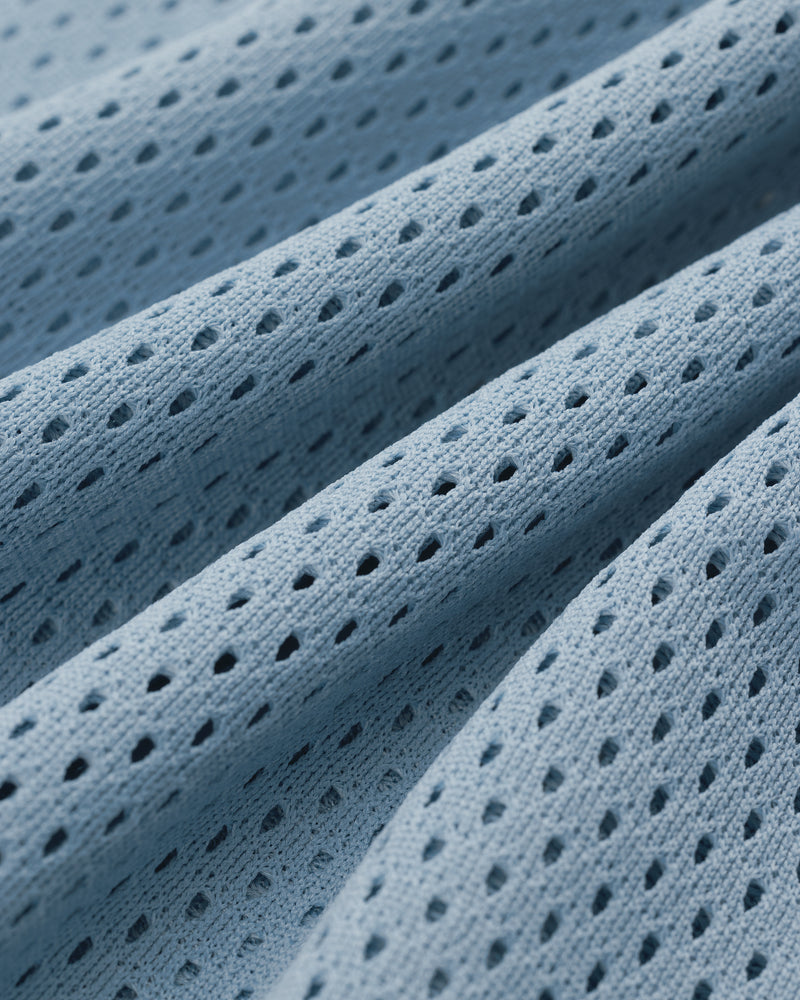 Close-up of Mesh Batting Practice Jersey featuring light blue perforated fabric with wavy folds and small holes.