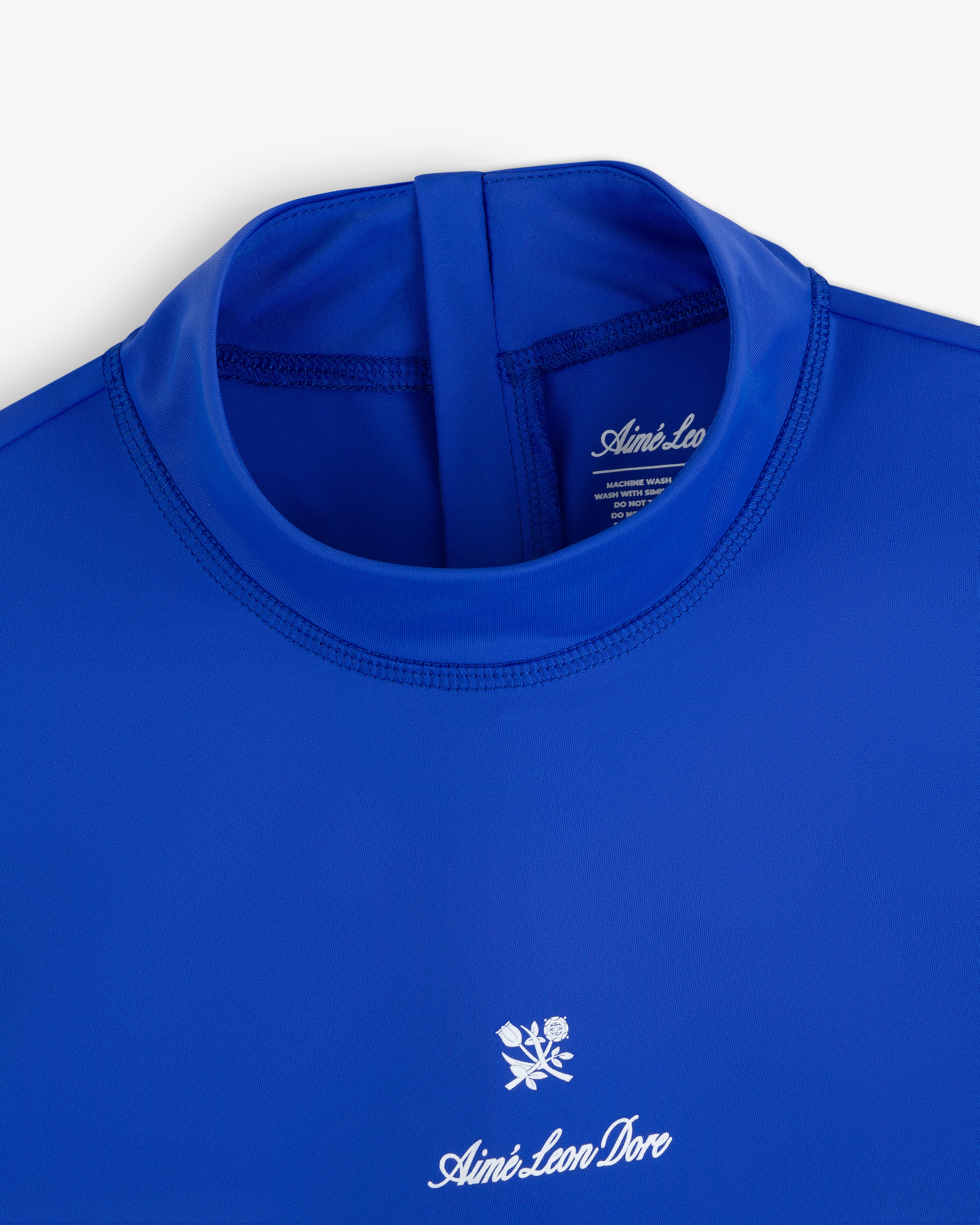 Blue Short Sleeve Crest Rash Guard with “Aimé Leon Dore” and a small white rose logo embroidered on the chest.