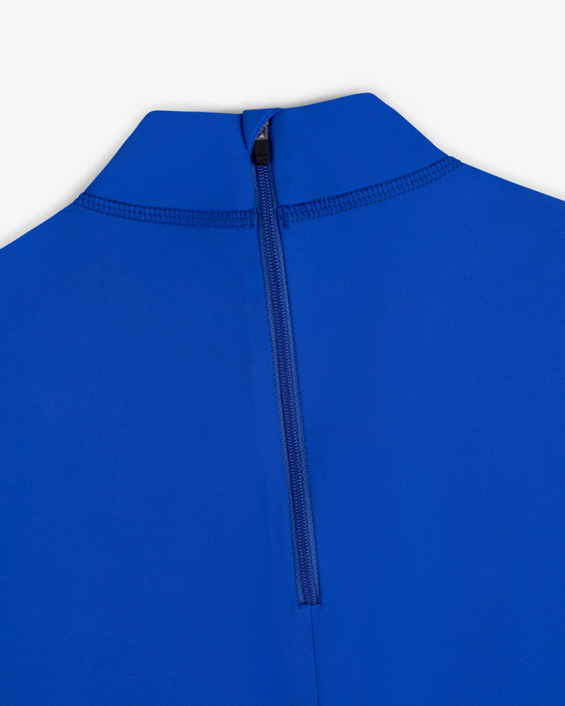 Close-up of a blue Short Sleeve Crest Rash Guard with a high collar and centered back zipper against a white background.