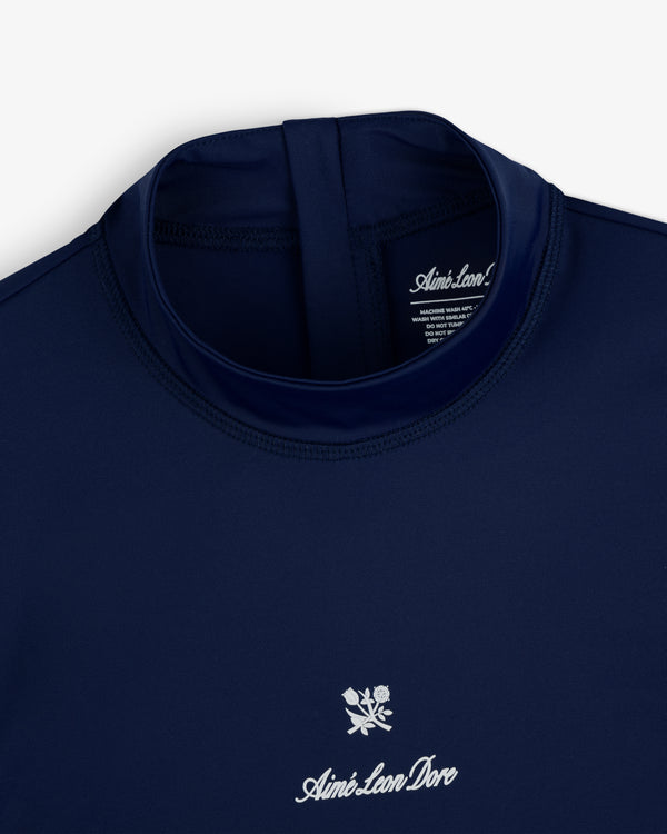 Navy blue Aimé Leon Dore Short Sleeve Crest Rash Guard with white logo and floral chest design, collar down view.