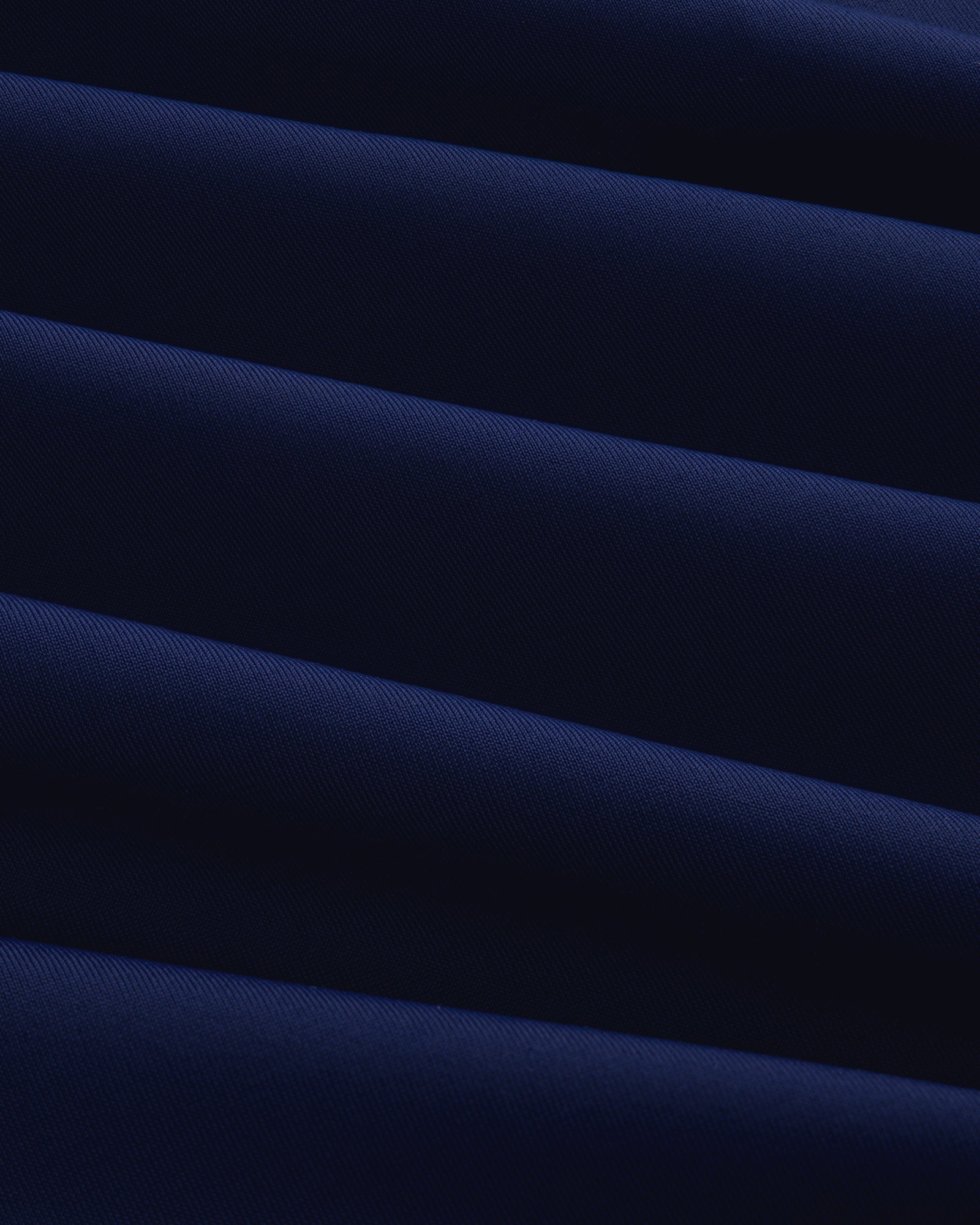 Close-up of the Short Sleeve Crest Rash Guard, showing folded dark blue fabric with ridged, diagonal texture.