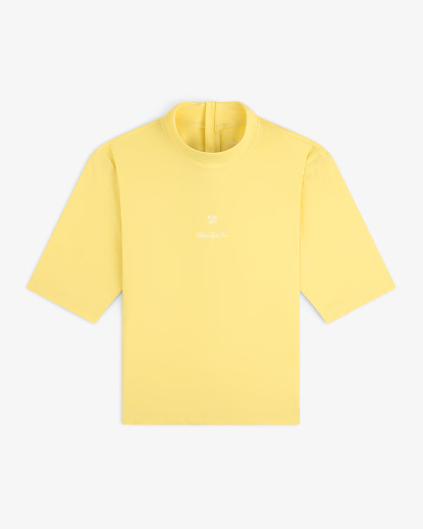 A yellow Short Sleeve Crest Rash Guard with a small white logo and text on the chest, laid flat on a white background.