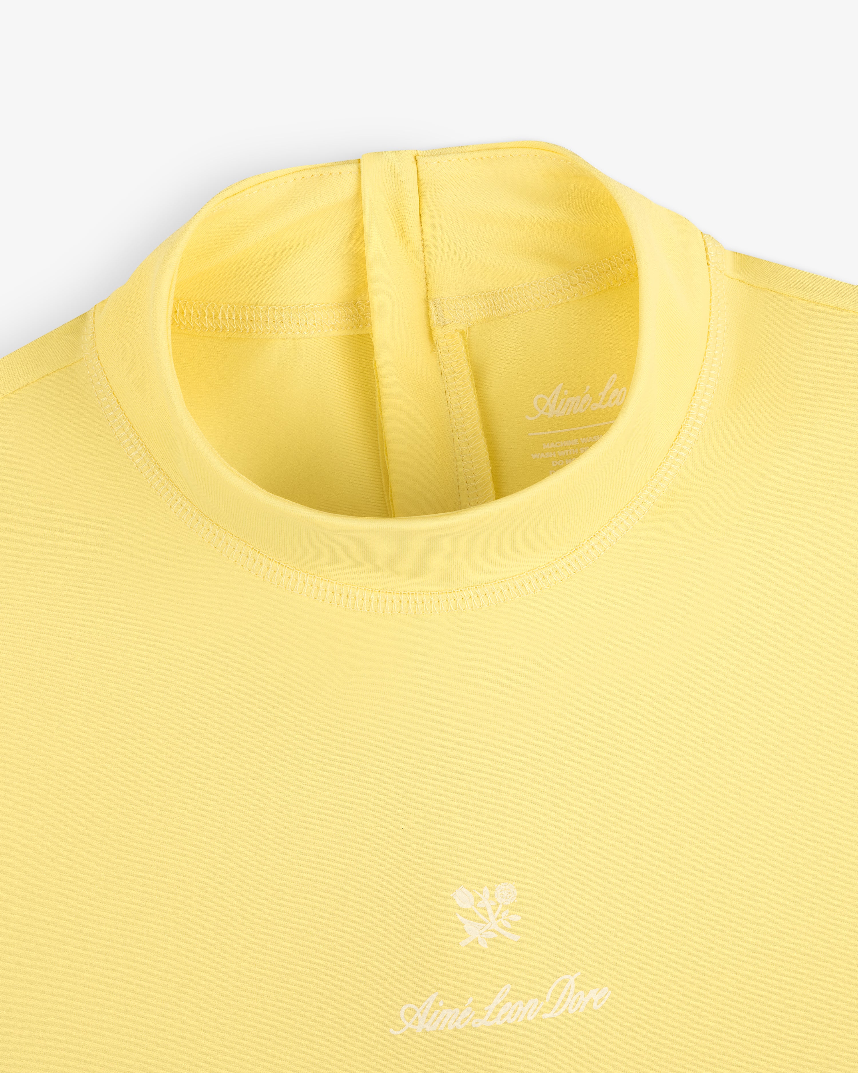 Yellow Short Sleeve Crest Rash Guard with Aimé Leon Dore and small white flower logo on the chest.