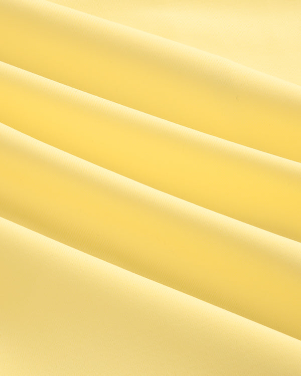 Close-up of soft, smooth light yellow fabric with gentle folds from a Short Sleeve Crest Rash Guard.