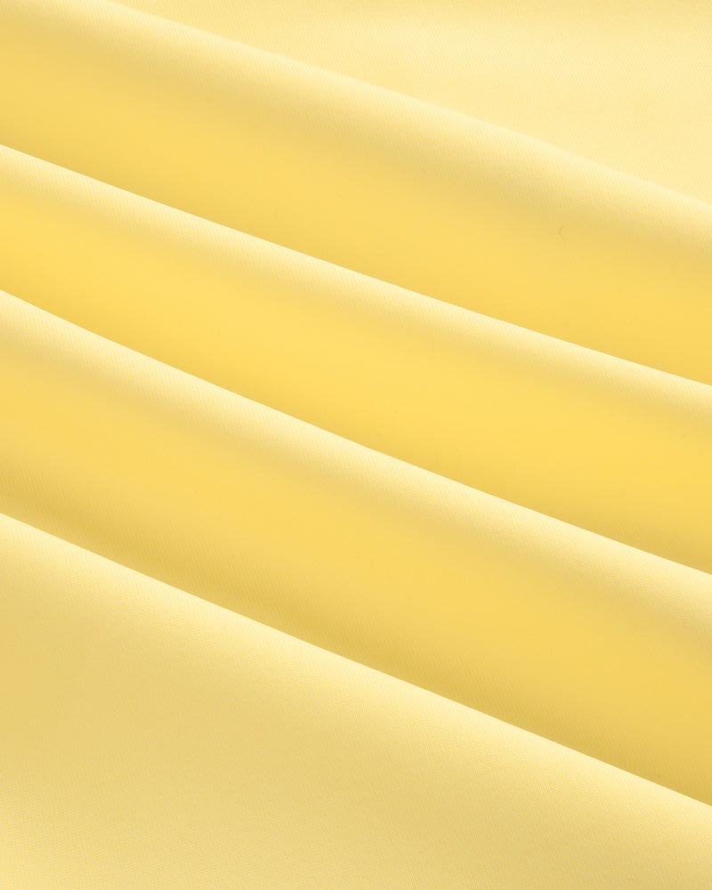 Close-up of soft, smooth light yellow fabric with gentle folds from a Short Sleeve Crest Rash Guard.