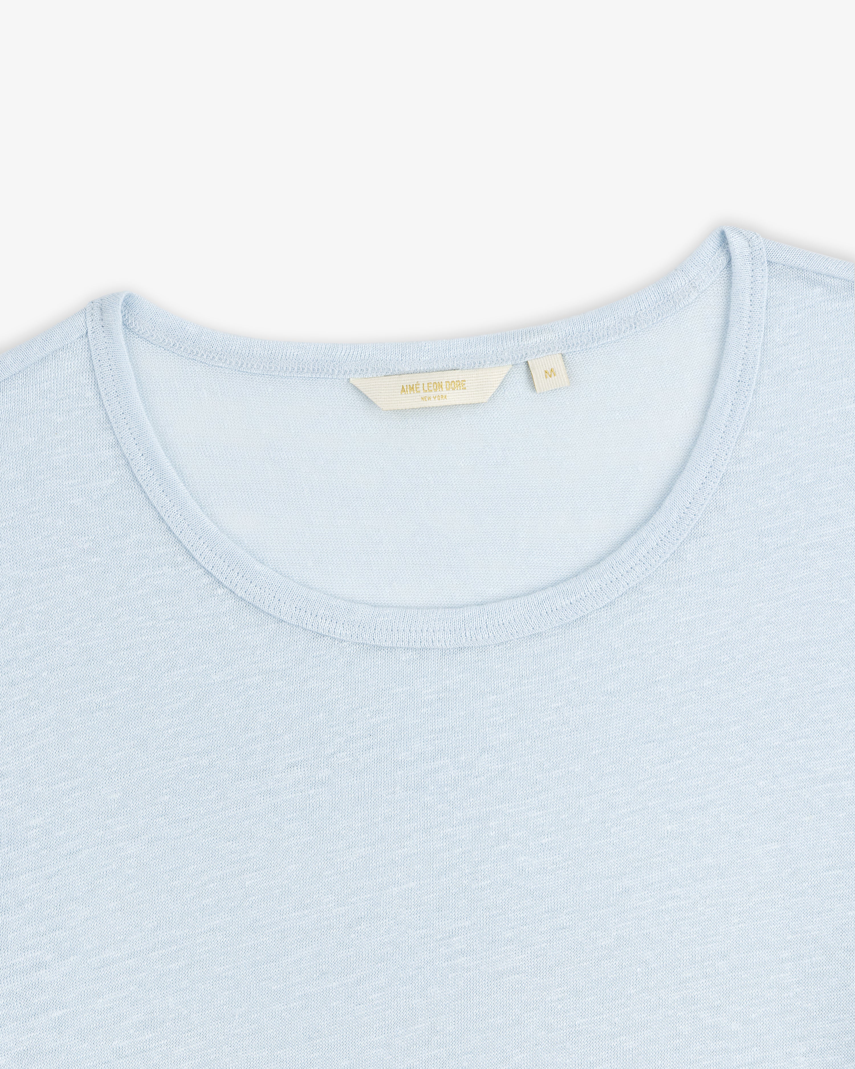 Light blue Linen Tee with a visible beige collar tag, displayed on a white background.