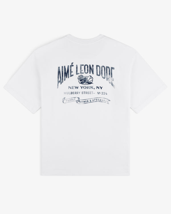 Neighborhood Pocket Tee: White T-shirt with blue AIMÉ LEON DORE text and New York, NY address on the back.