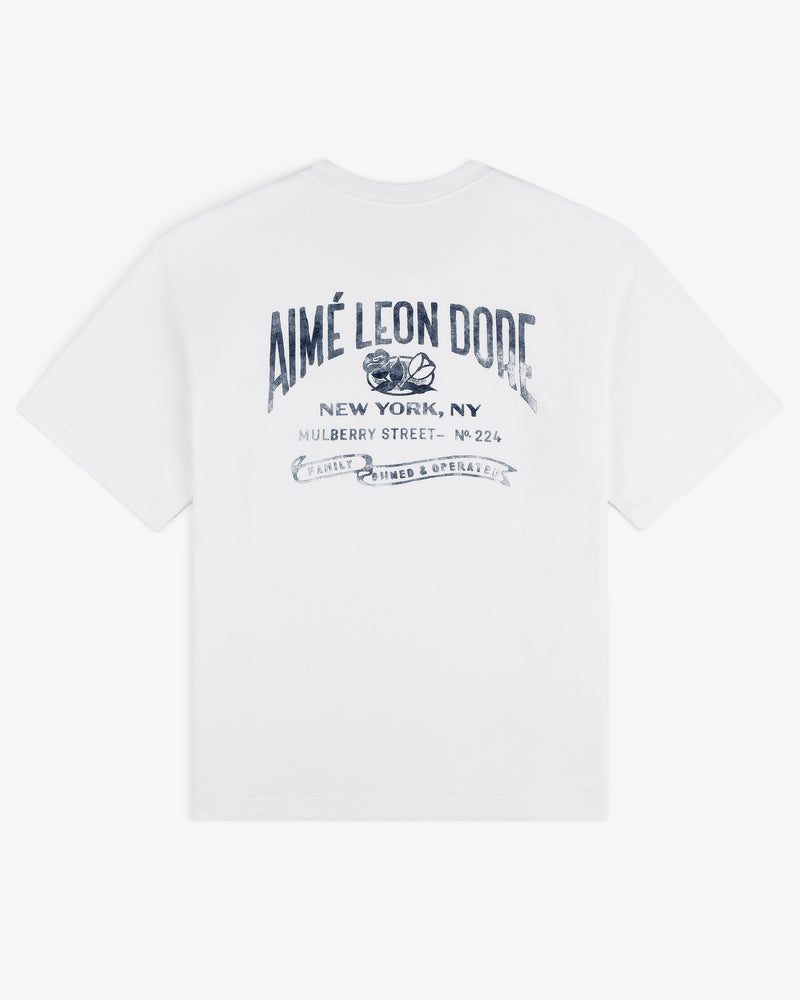 Neighborhood Pocket Tee: White T-shirt with blue AIMÉ LEON DORE text and New York, NY address on the back.