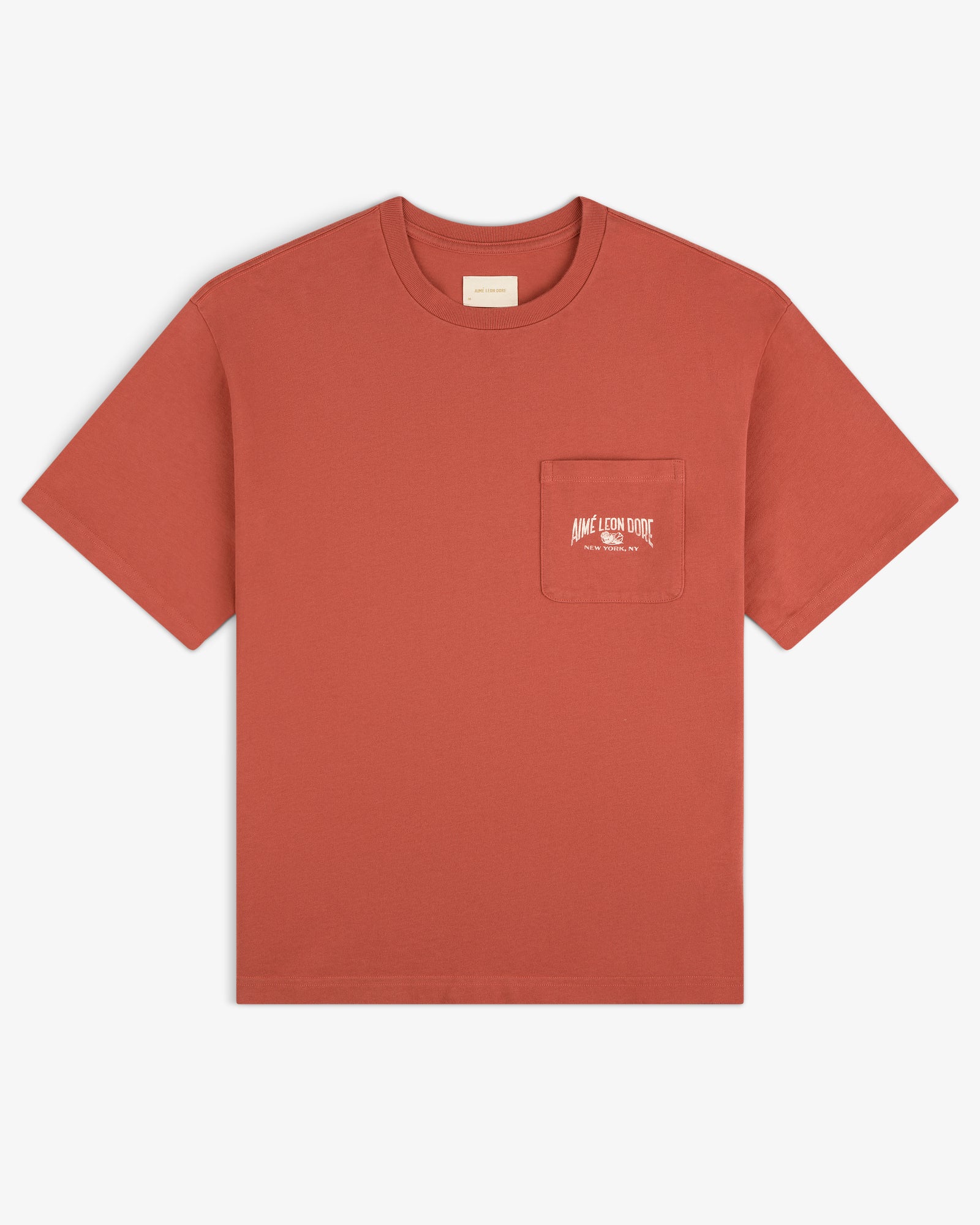 Neighborhood Pocket Tee in rust with short sleeves, chest pocket, and small white logo plus text.