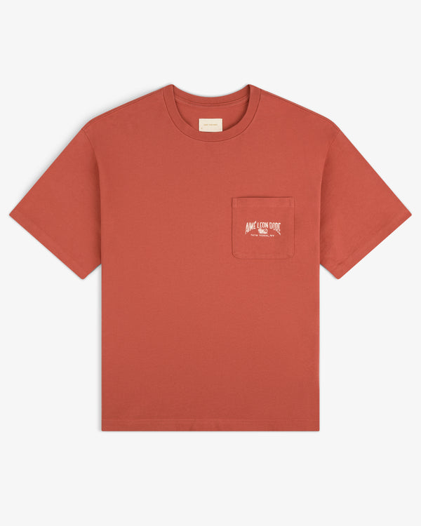 Neighborhood Pocket Tee in rust with short sleeves, chest pocket, and small white logo plus text.