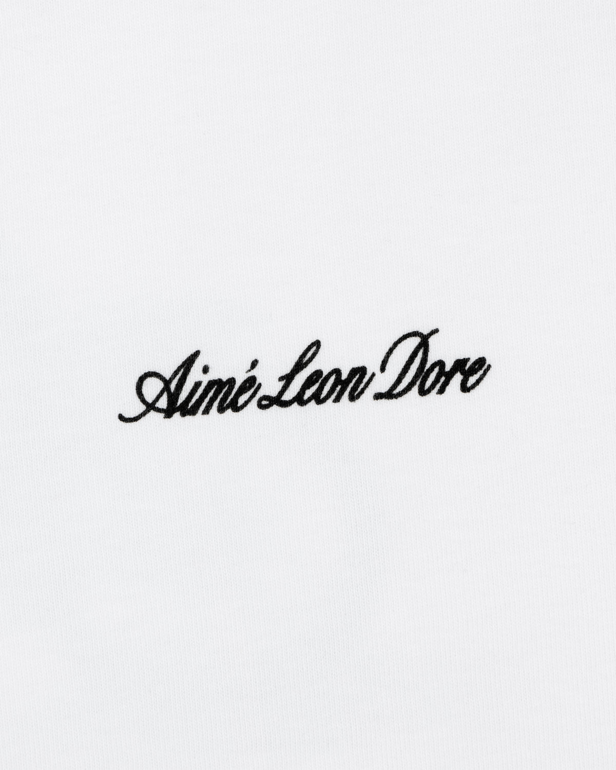 Black script text Aimé Leon Dore is embroidered on the white Super Cub Tee.