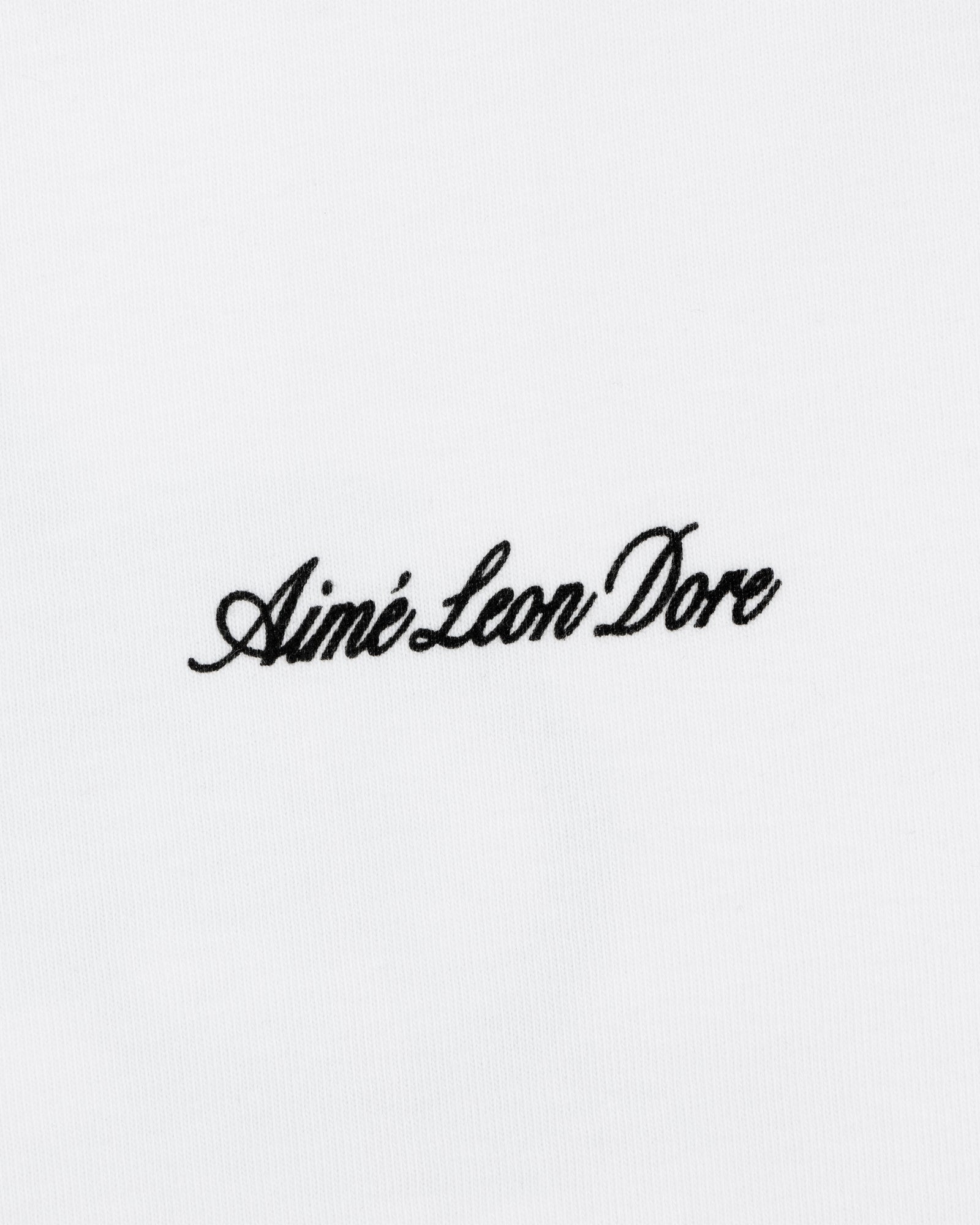 Black script text Aimé Leon Dore is embroidered on the white Super Cub Tee.