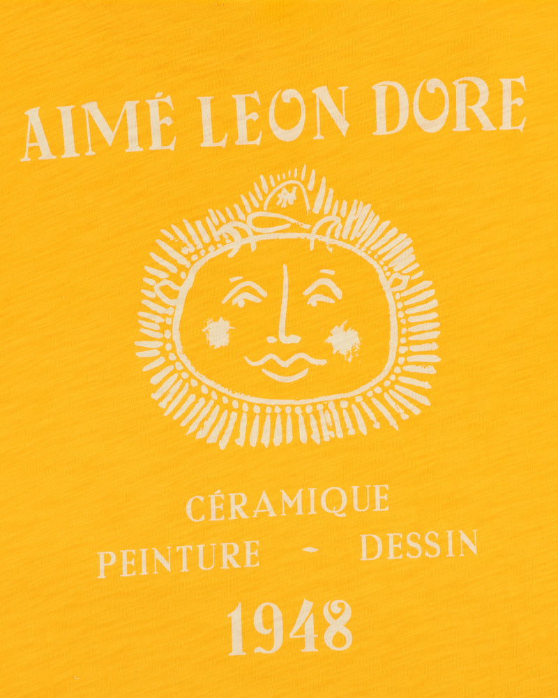 Yellow background Artiste Pocket Tee with AIMÉ LEON DORE, sun face, and CÉRAMIQUE PEINTURE DESSIN 1948 text.