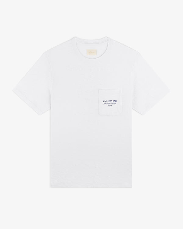 Artiste Pocket Tee: white short-sleeve t-shirt with chest pocket, small printed logo, and text.