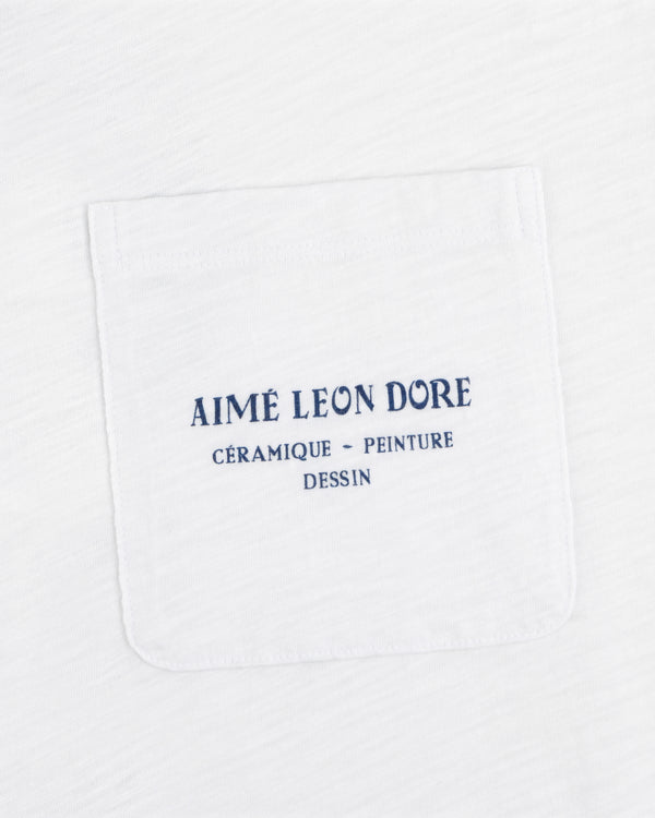 Artiste Pocket Tee: White shirt with chest pocket, blue text reads AIMÉ LEON DORE CÉRAMIQUE - PEINTURE DESSIN.