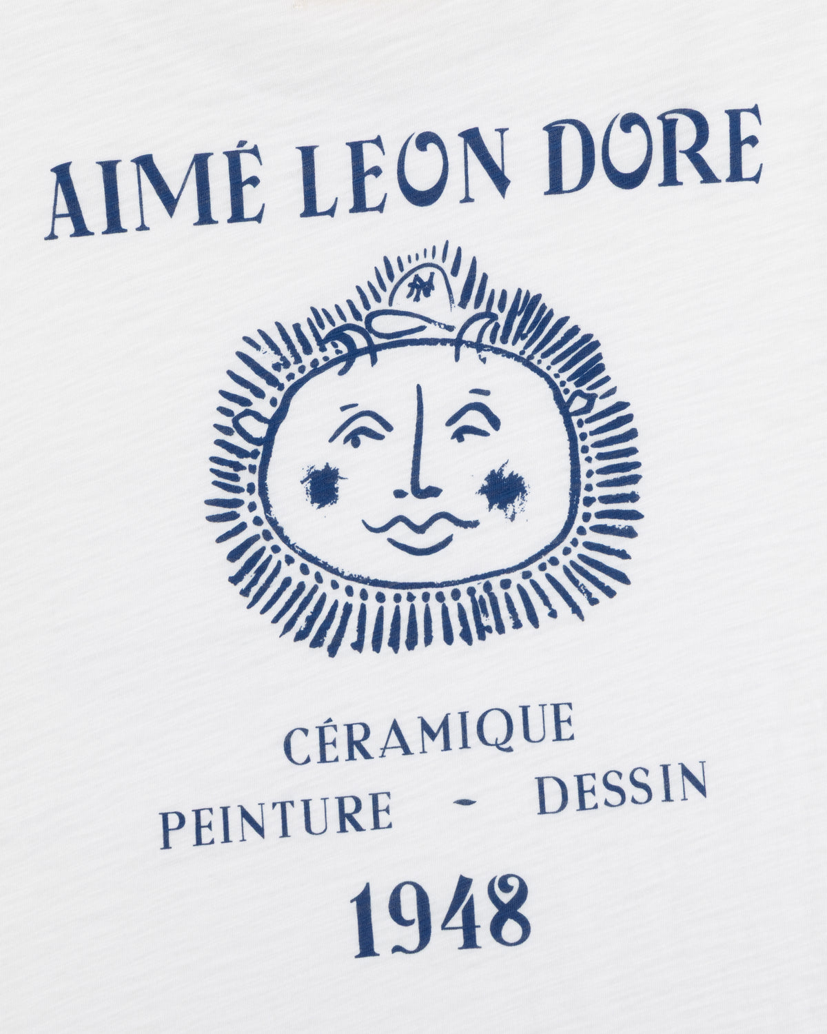 White Artiste Pocket Tee with blue AIMÉ LEON DORE above a sun-face and CÉRAMIQUE PEINTURE DESSIN 1948 text.