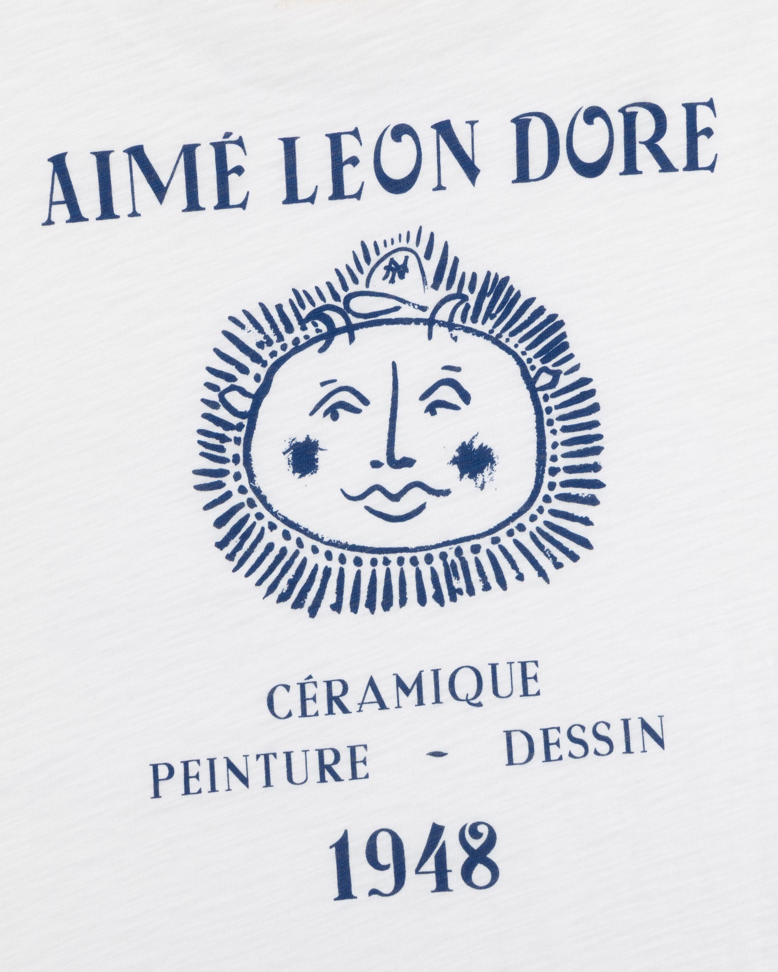 White Artiste Pocket Tee with blue AIMÉ LEON DORE above a sun-face and CÉRAMIQUE PEINTURE DESSIN 1948 text.