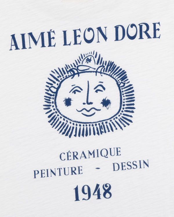White Artiste Pocket Tee with blue AIMÉ LEON DORE above a sun-face and CÉRAMIQUE PEINTURE DESSIN 1948 text.