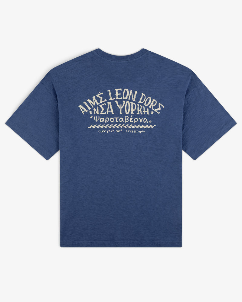 Taverna Tee: Blue shirt with white Greek and English text and graphics on back, reads AIMÉ LEON DORE ΝΕΑ ΥΟΡΚΗ.