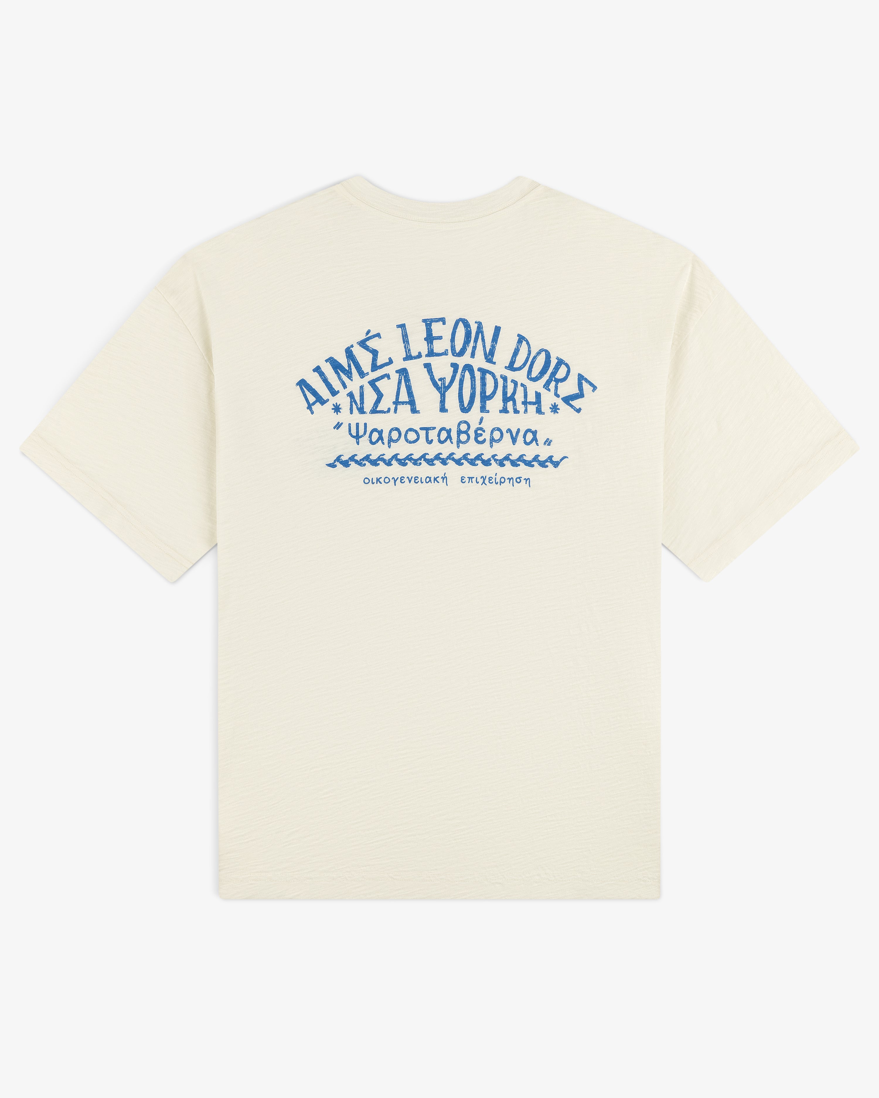 Off-white Taverna Tee with blue Greek text and "AIMÉ LEON DORE" in stylized letters on the back.